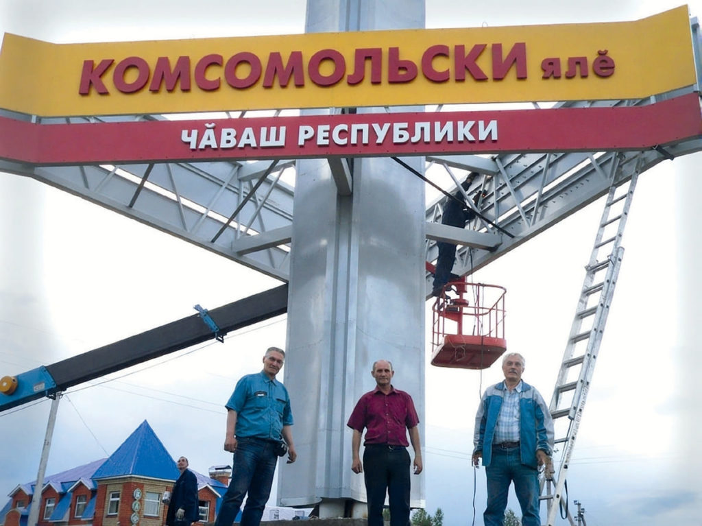Стела на въезде в село Комсомольское, созданная на ЗАО «Промэнерго». На фото: Анатолий Иванов (крайний слева) и Вячеслав Иванов (крайний справа)